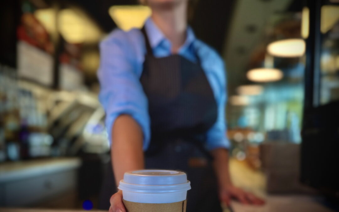A barista holding a cup of coffee.